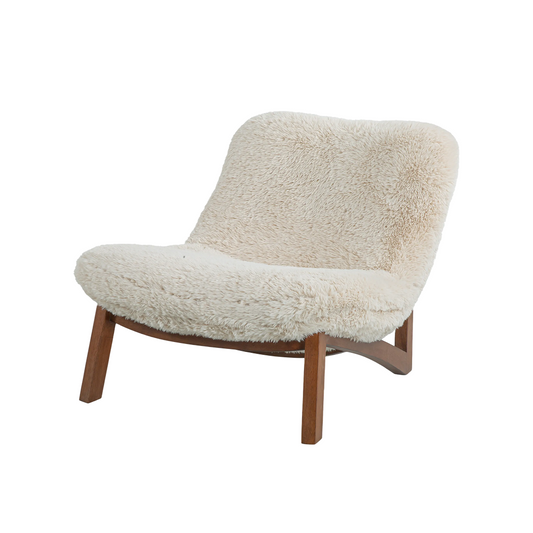 A modern lounge chair with a thick, shaggy off-white sheepskin or faux fur upholstery and angled medium-brown wooden legs.